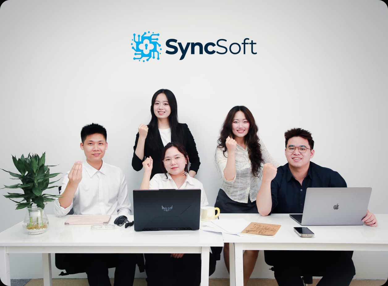 The SyncSoft.AI team collaborating around a table with laptops